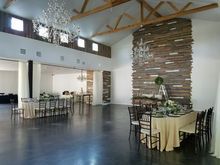 Elegant event space with chandeliers, tables set for dining, and a wood accent wall.