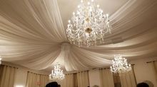 Elegant room with fabric draped ceiling and crystal chandeliers.