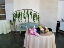 A light blue sofa with hats on a table in front of a wall with a mural of vines.