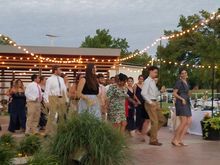 People dancing outdoors under string lights at an evening event.