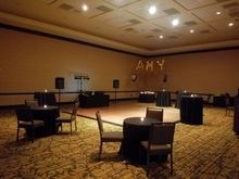 Empty event room with black-covered tables, dance floor, and the name 