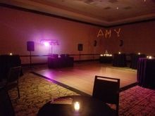 Empty event space with dance floor, DJ setup, tables, ambient lighting, and 