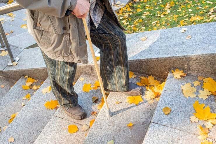 Person walking up outdoor stone steps covered with yellow autumn leaves