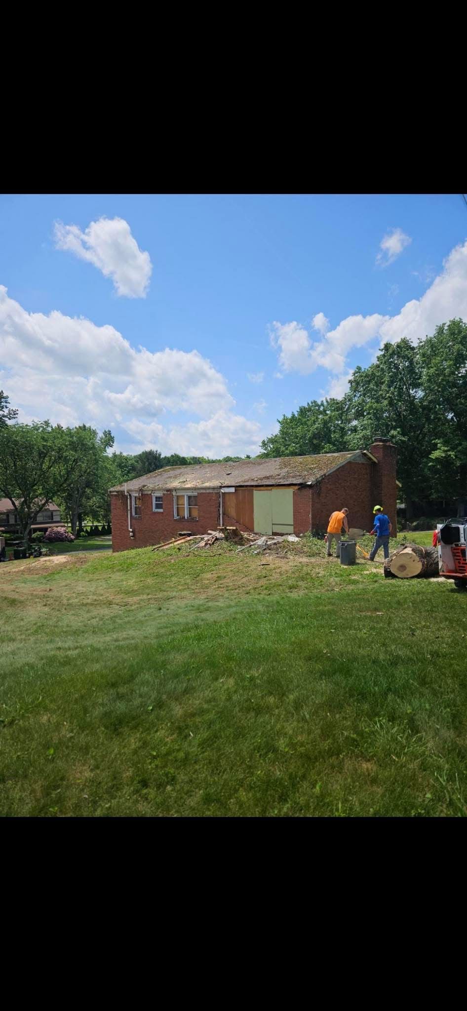 A brick house is sitting in the middle of a lush green field.