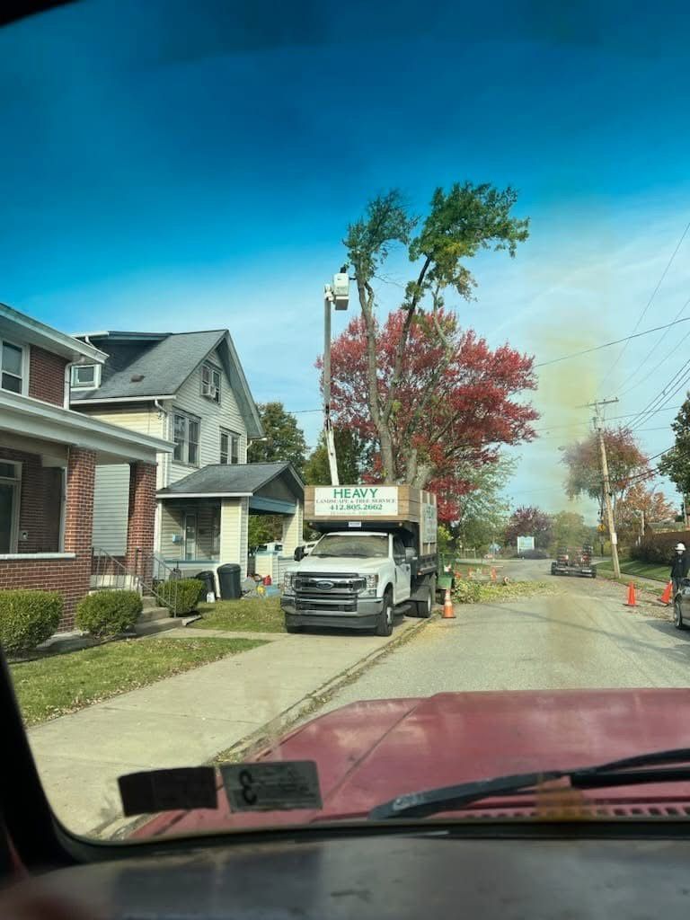 A truck is driving down a street next to a house.