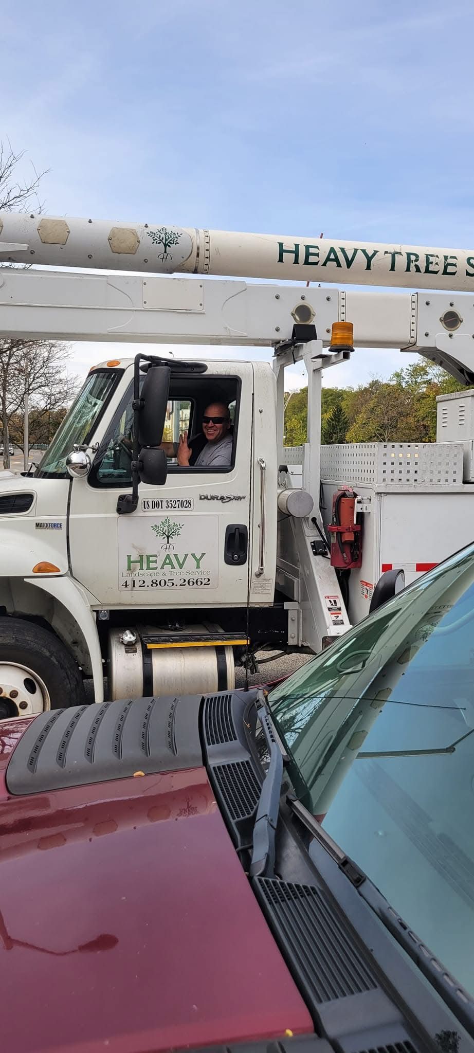 A man is driving a crane truck next to a red truck.