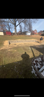 A shadow of a person is cast on the grass in a yard.