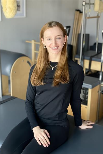 A woman is sitting on a yoga mat in a gym.