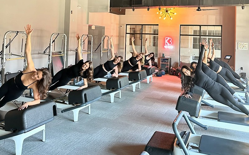 A group of women are doing exercises on pilates machines in a gym.