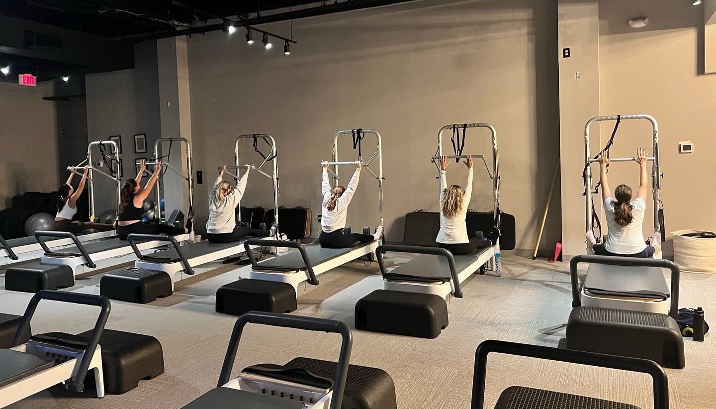 A group of people are using pilates machines in a gym.