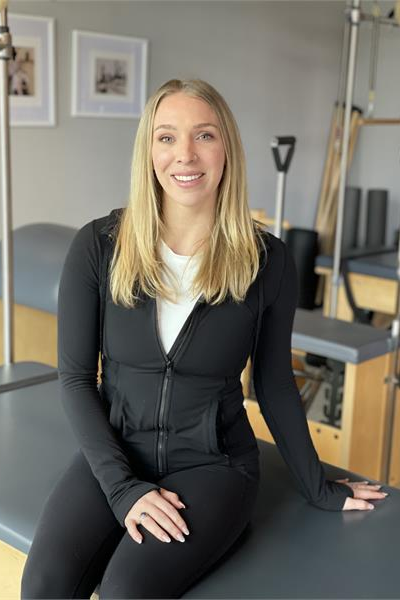 A woman is sitting on a yoga mat in a gym.