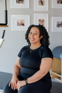A woman in a black shirt is sitting on a table and smiling.