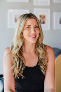 The woman is wearing a black tank top and smiling for the camera.