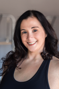 A woman in a black tank top is smiling for the camera.