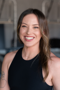 A woman in a black tank top is smiling for the camera.