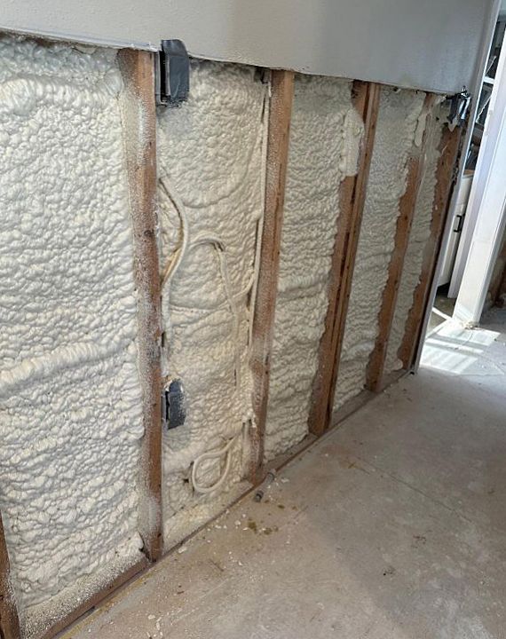 Wall studs with spray foam insulation; electrical boxes and wires visible.