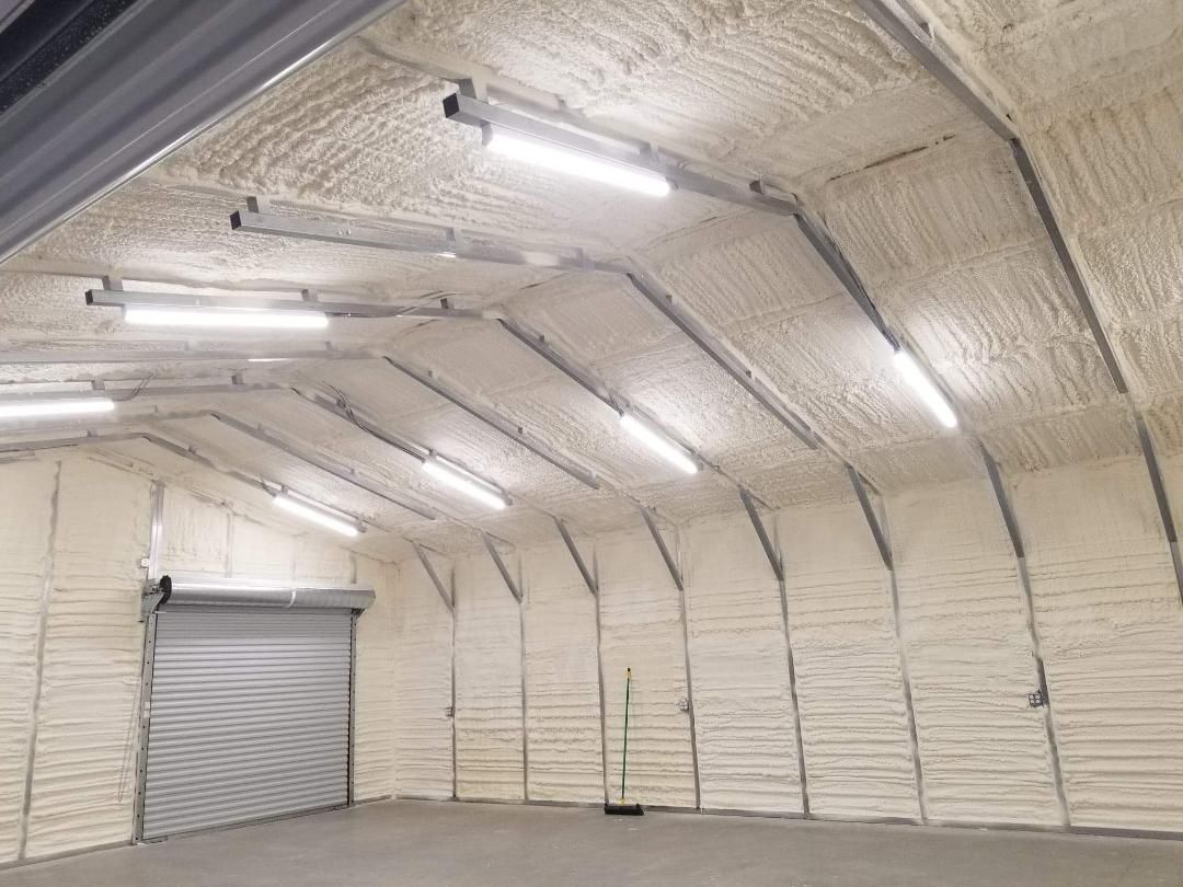 Interior of a light-filled building with arched ceiling and walls covered in light brown foam insulation.