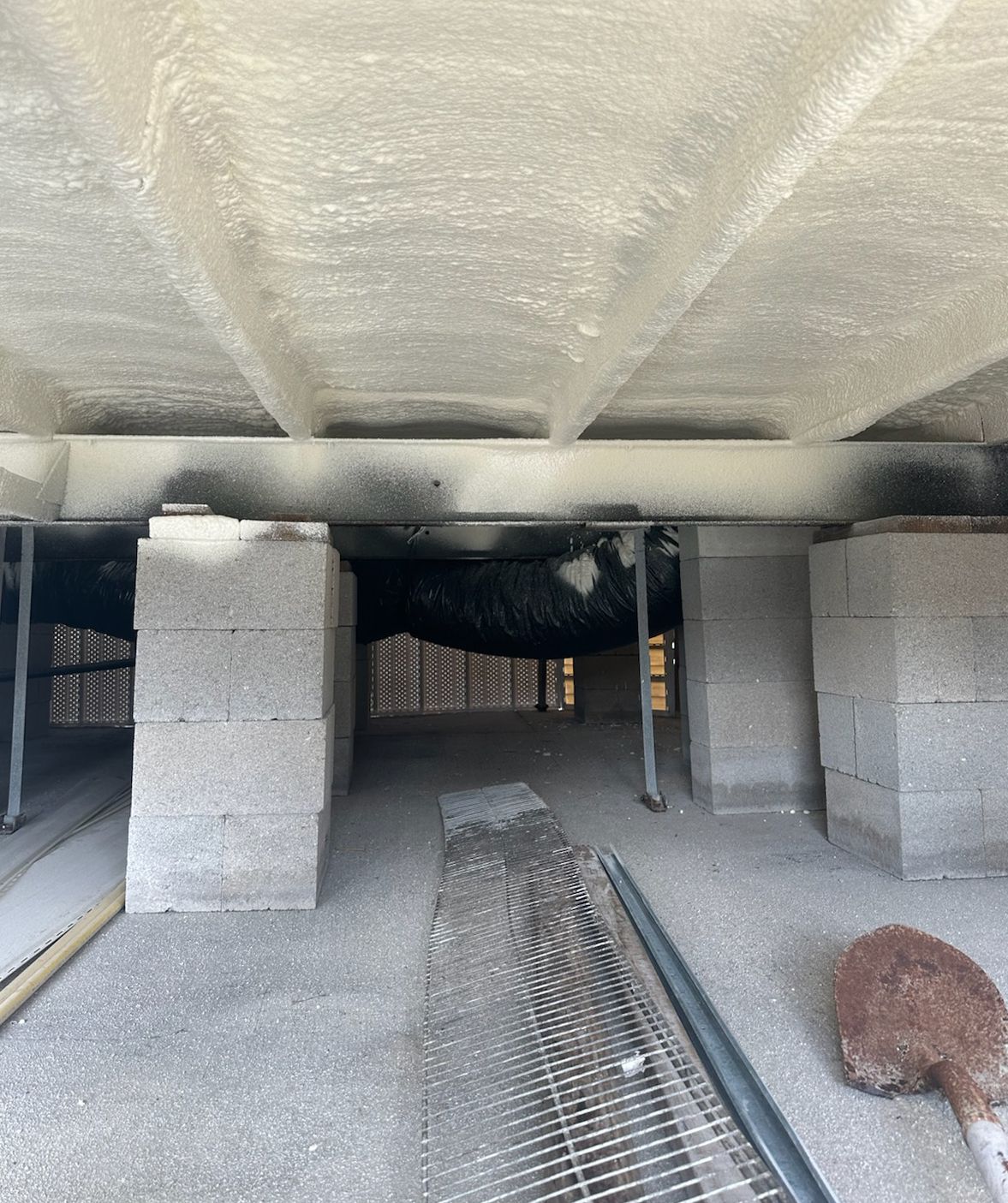 Underneath of a mobile home with cinder block supports and some rusted metal.