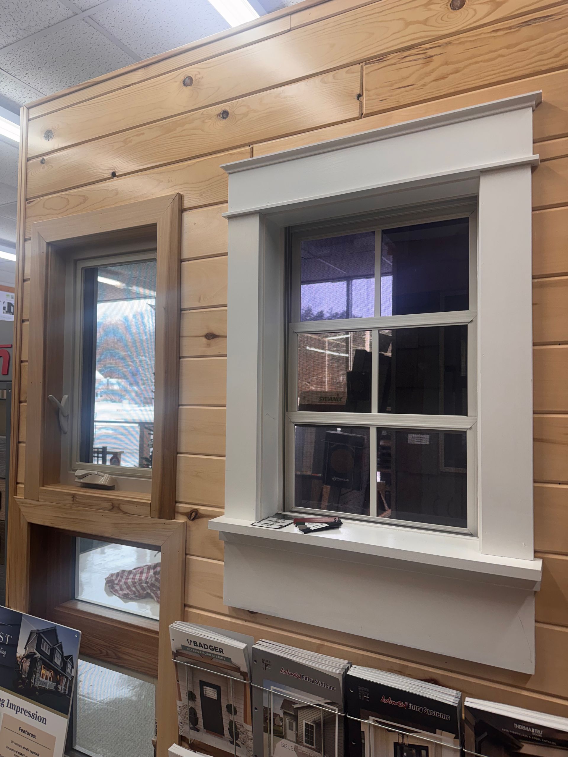 Two windows on a wooden wall: one plain, one with white trim.