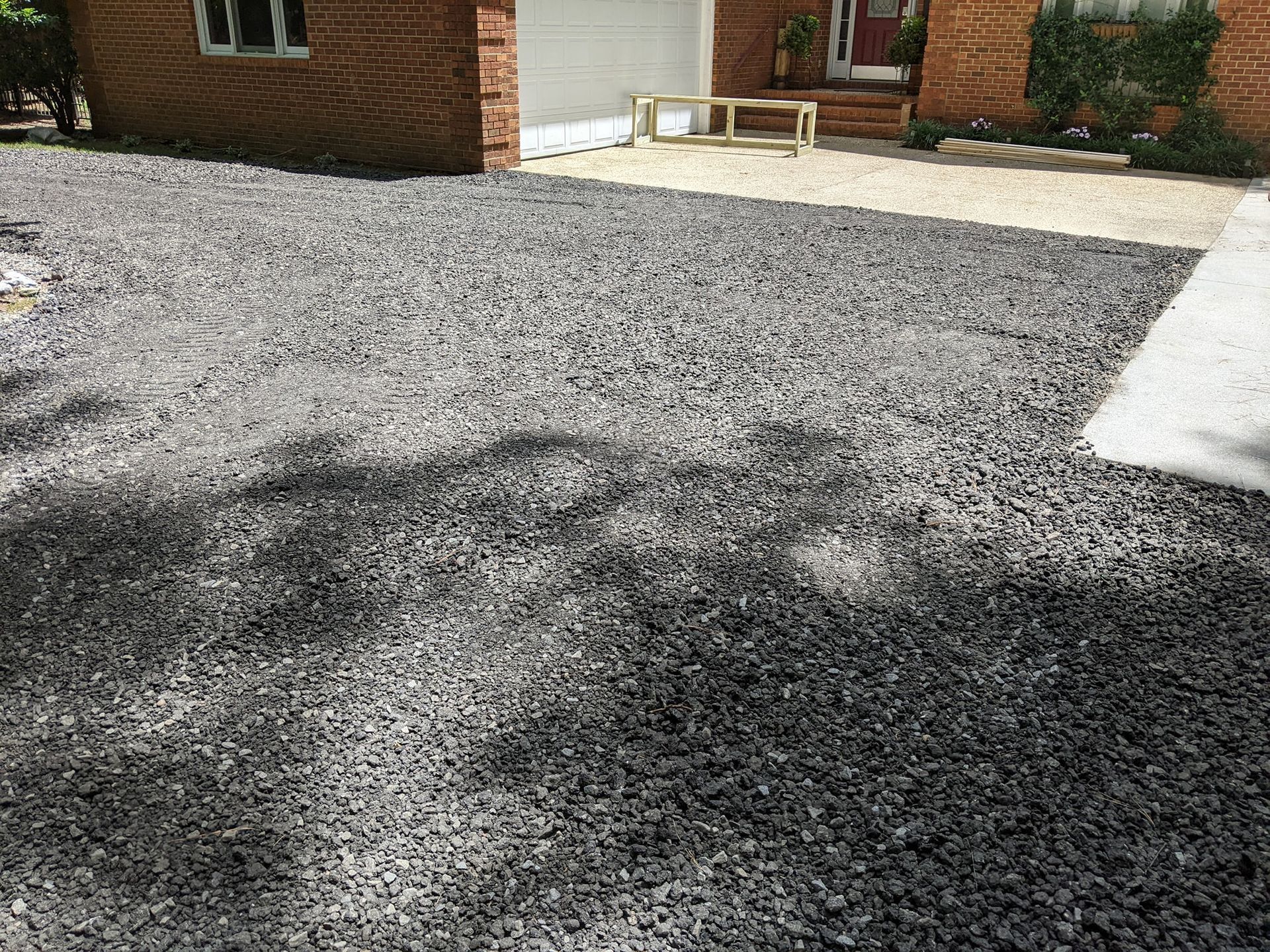 a driveway with gravel and a brick house in the background .