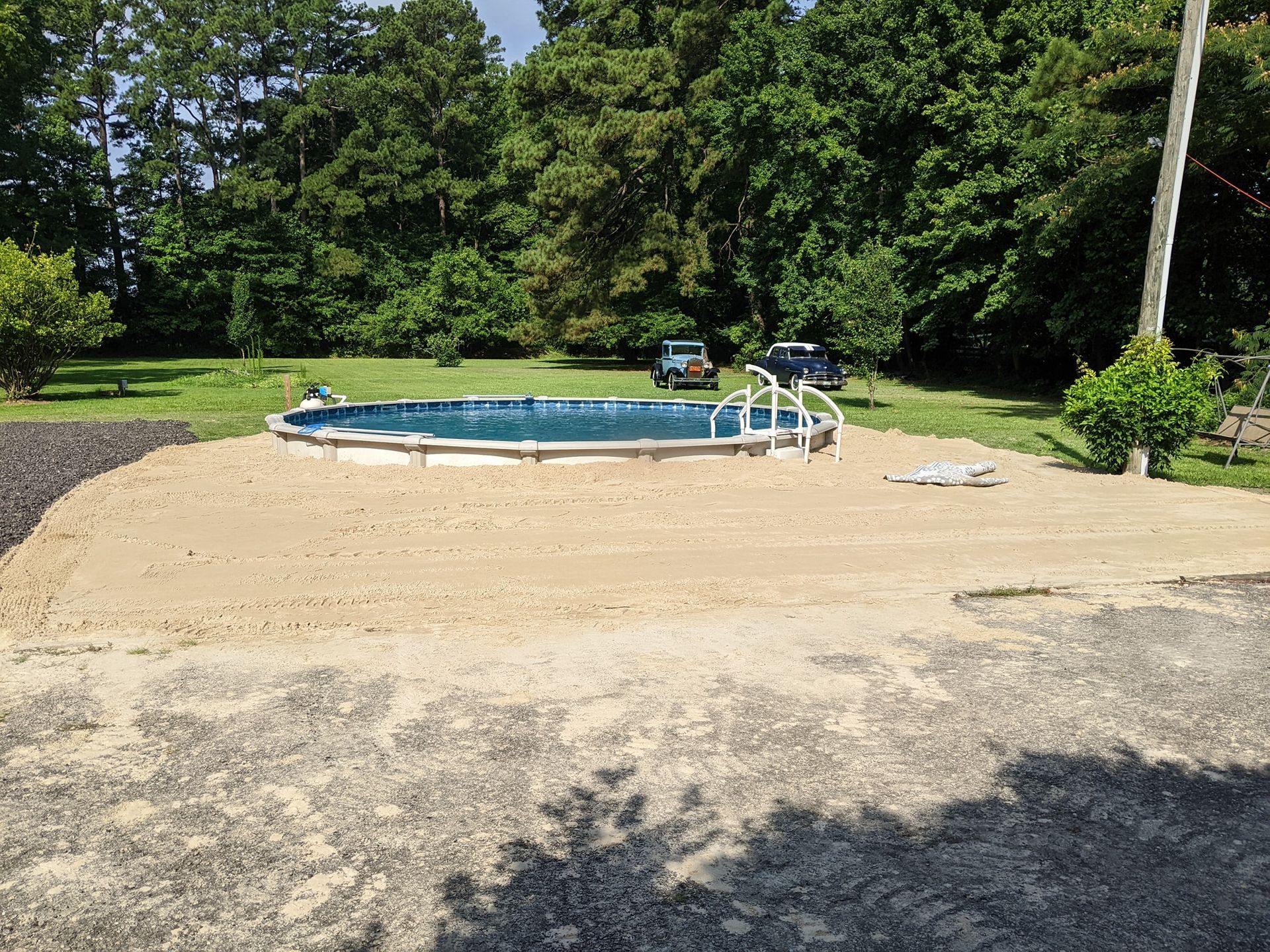 a swimming pool is sitting in the middle of gravel.