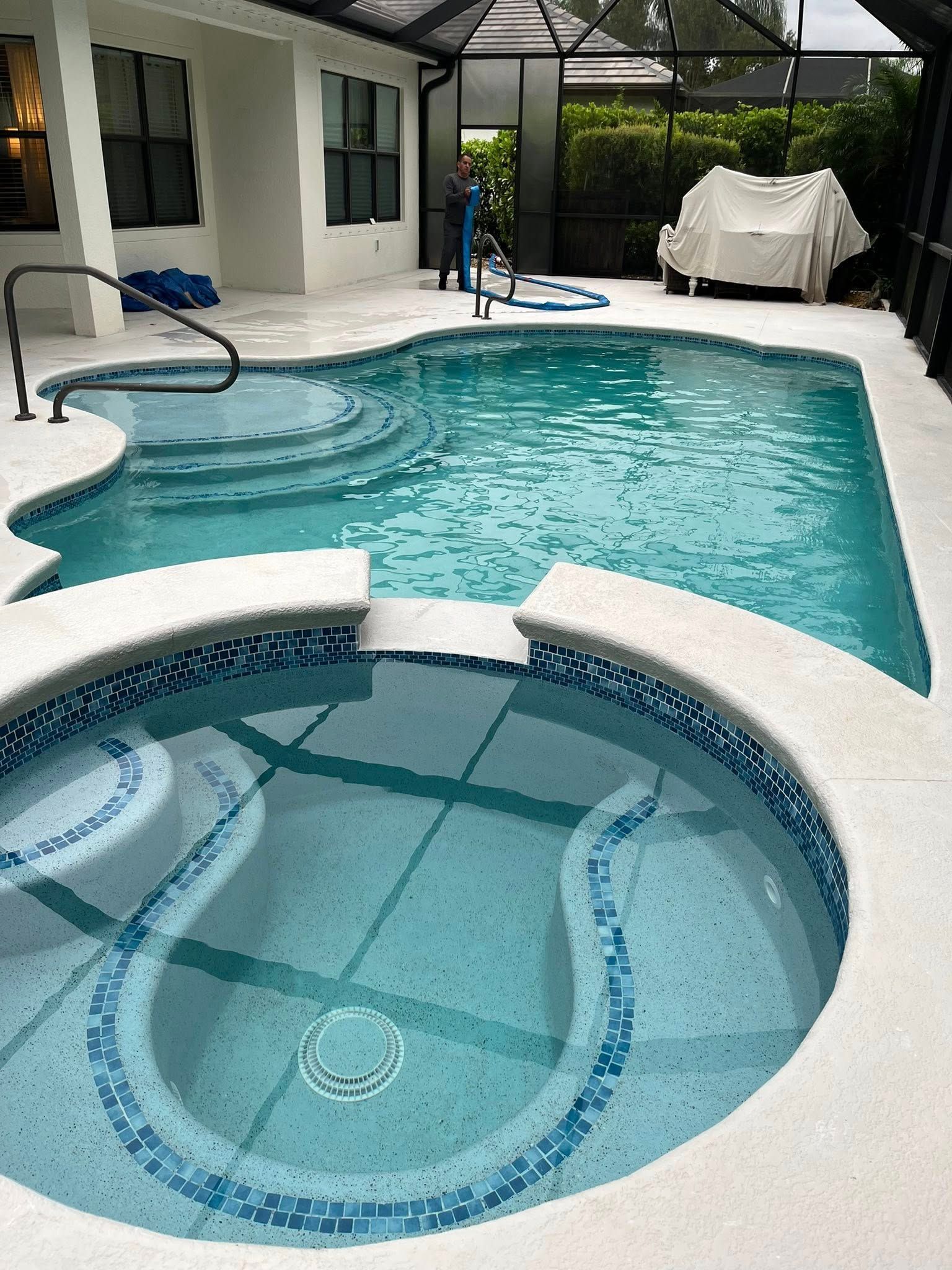 A large swimming pool with a hot tub next to it.