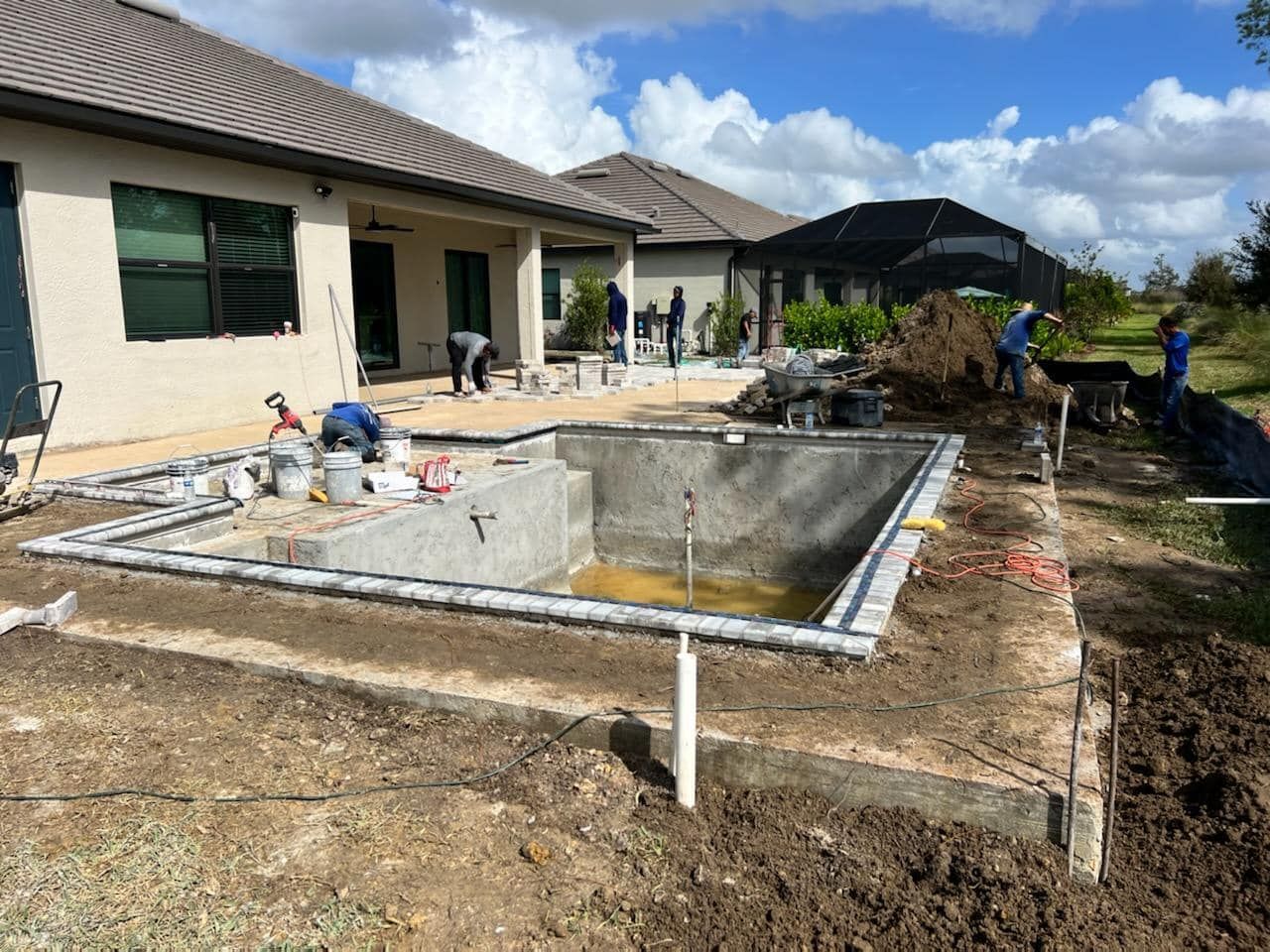 A swimming pool is being built in the backyard of a house.