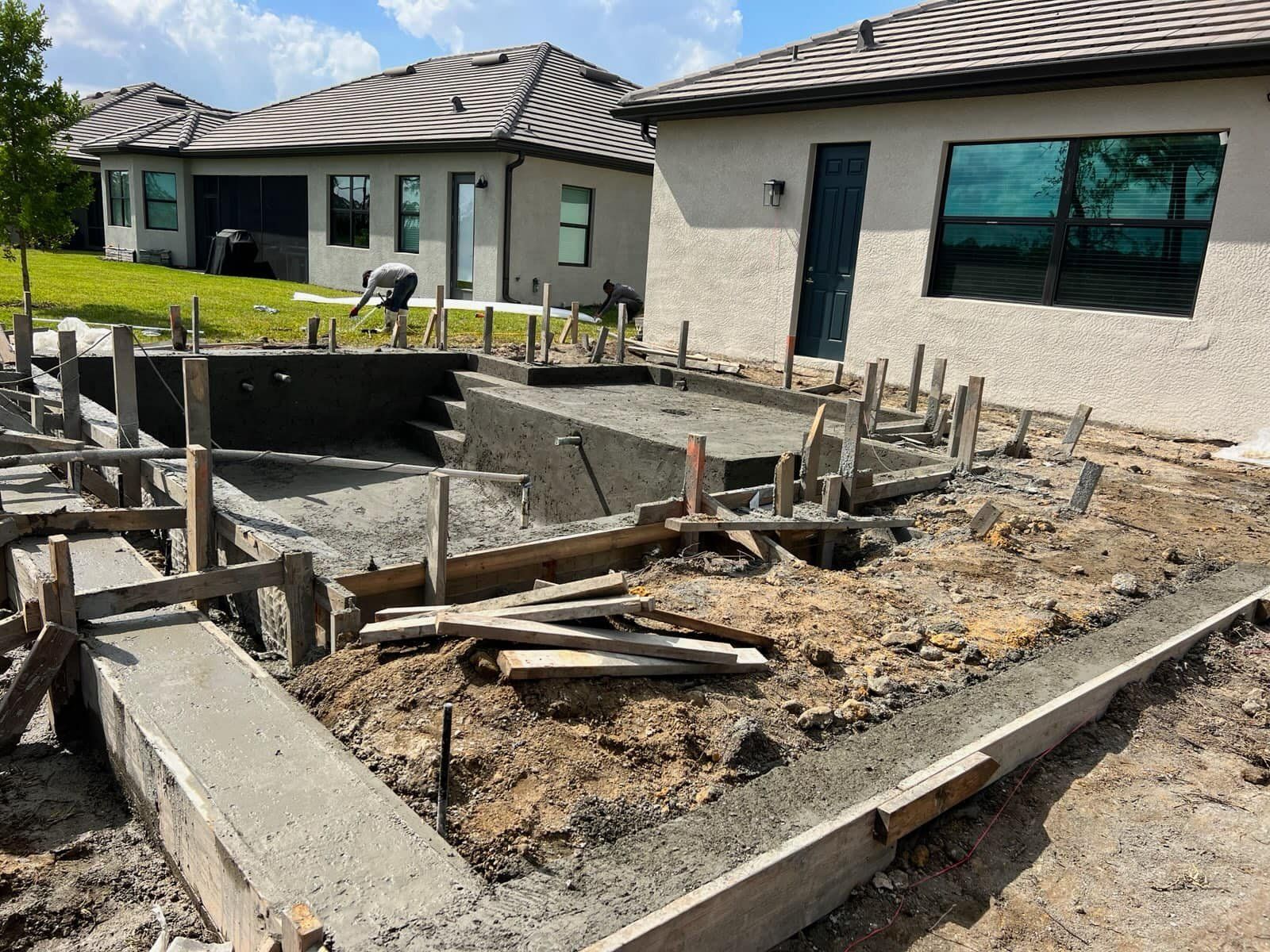 A house is being built with a swimming pool in the background.