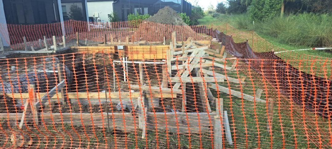 A construction site with a fence around it and a house in the background.