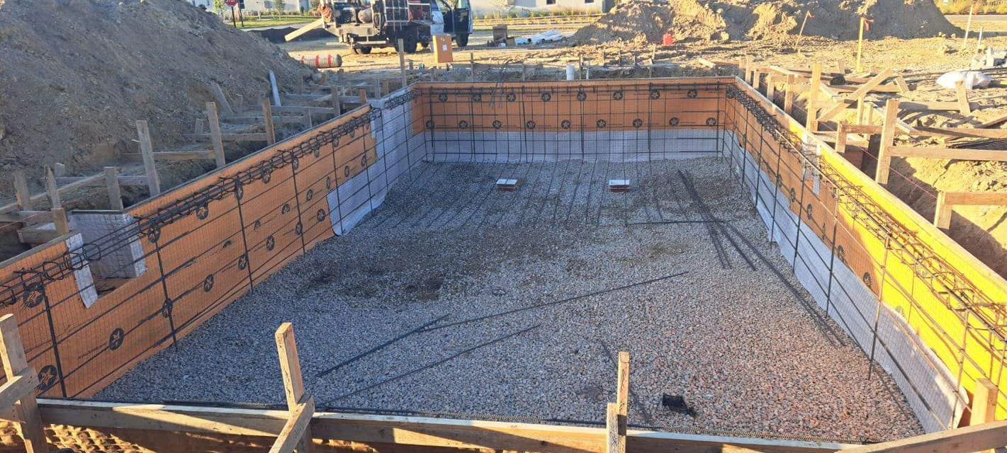 A large swimming pool is being built in a dirt field.