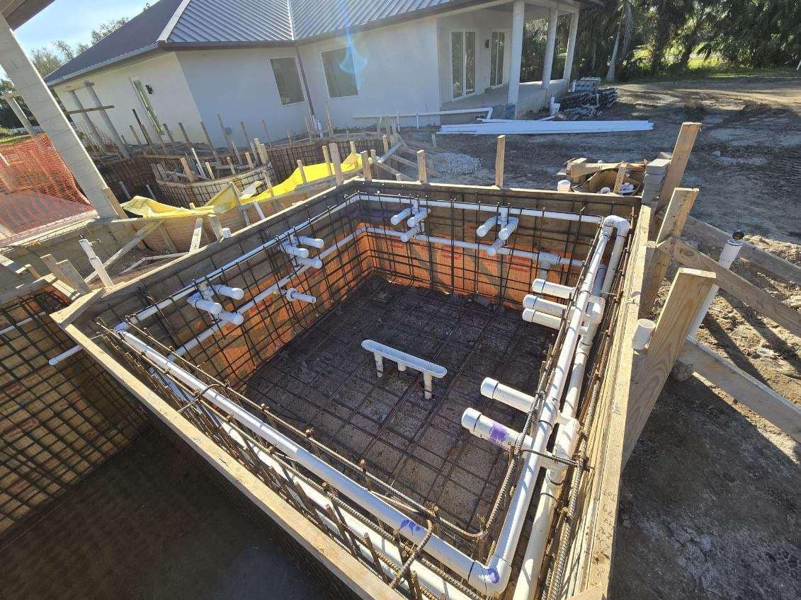A swimming pool is being built in the backyard of a house.