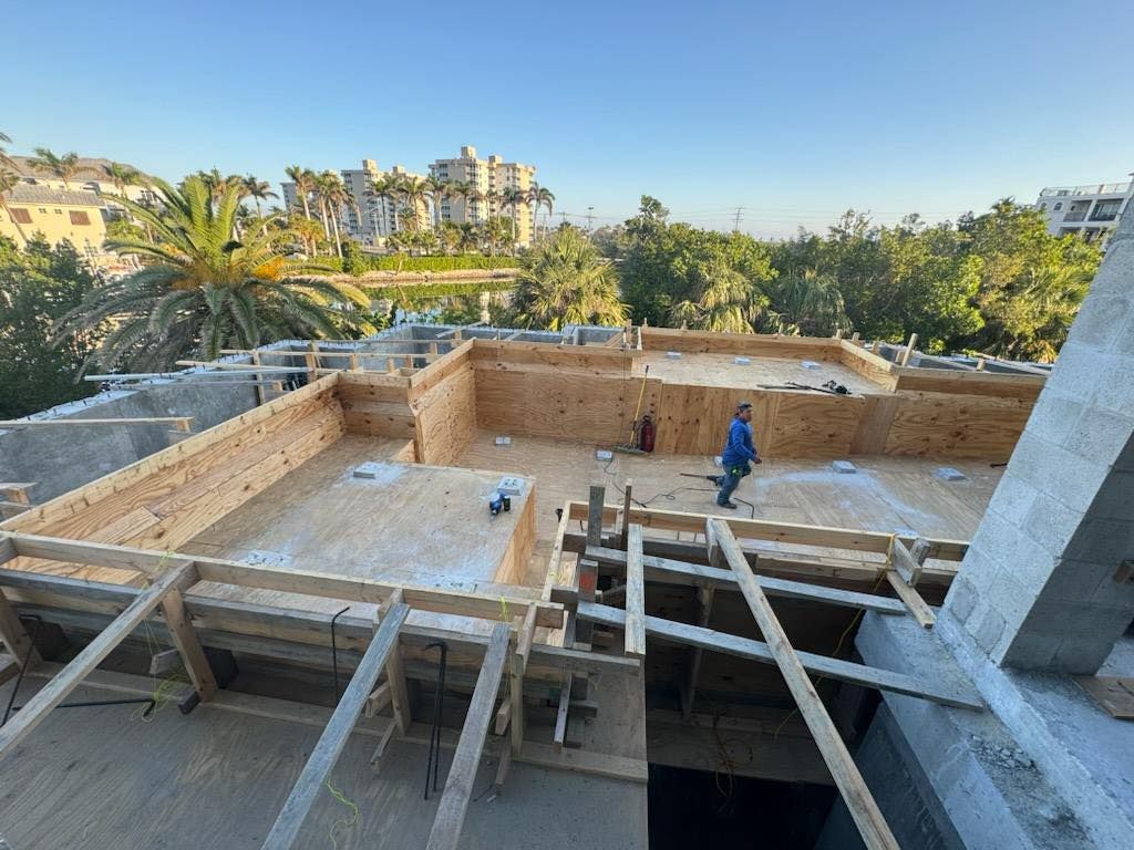 A man is standing on the roof of a building under construction.