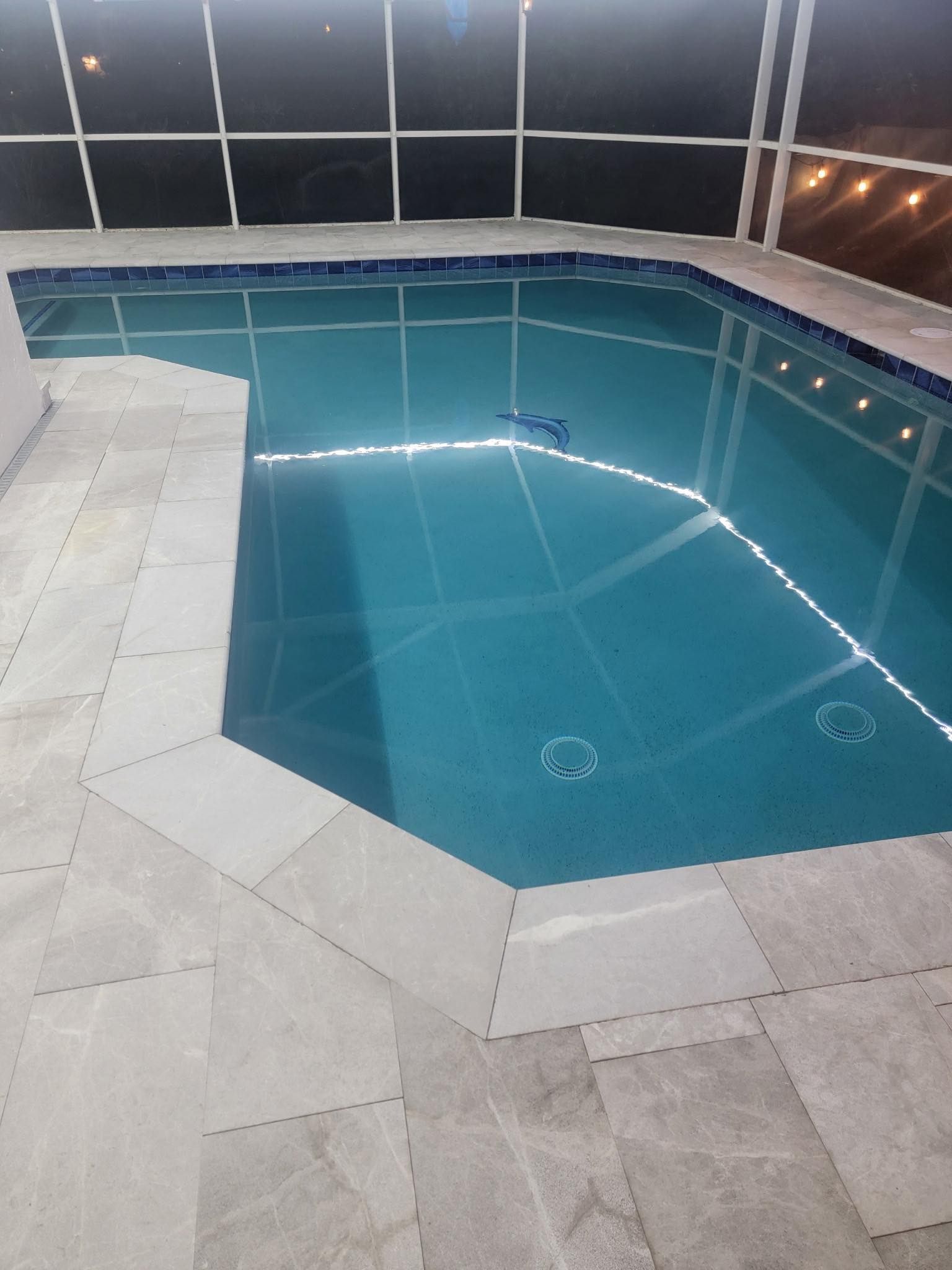 A large swimming pool in a screened in area at night