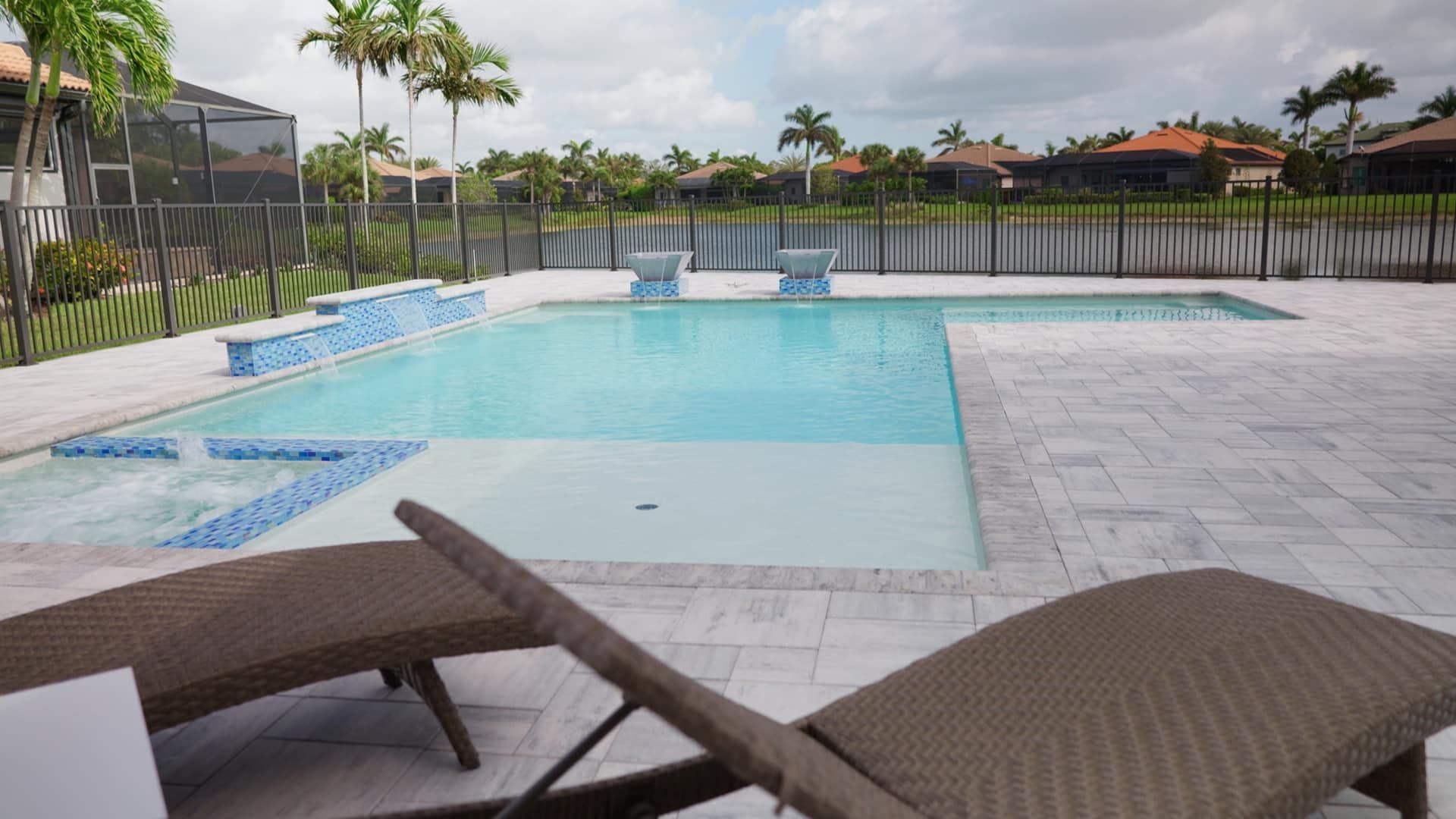 A large swimming pool surrounded by lawn chairs and palm trees.