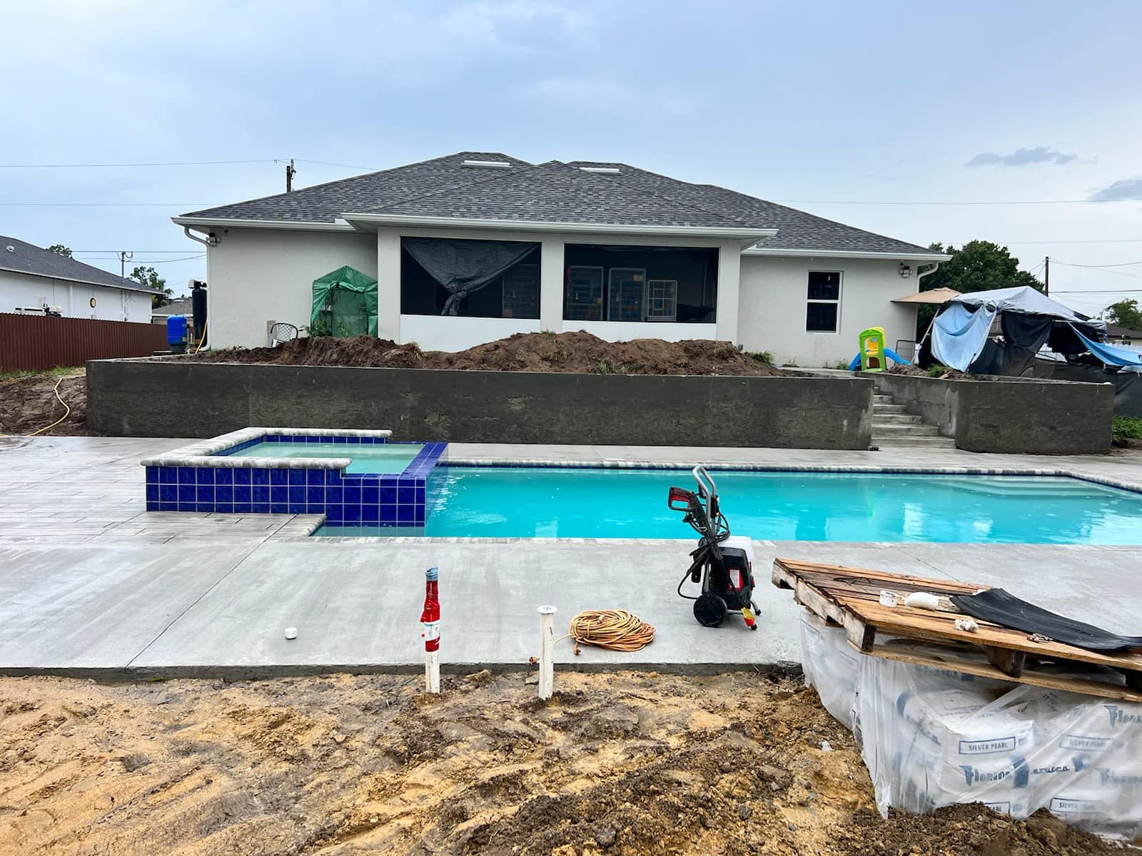 A large swimming pool is being built in the backyard of a house.