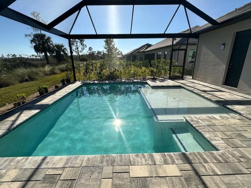 A large swimming pool is surrounded by a screened in area