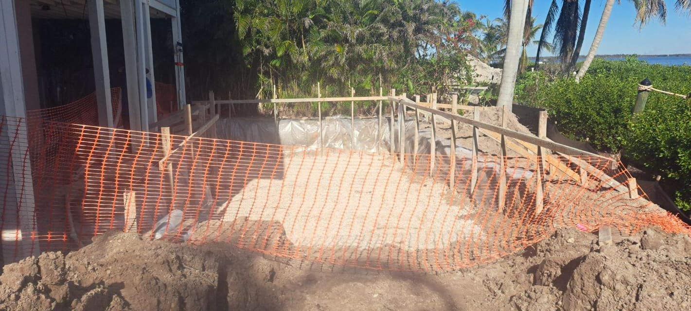 A large pile of dirt is sitting in front of a building under construction.