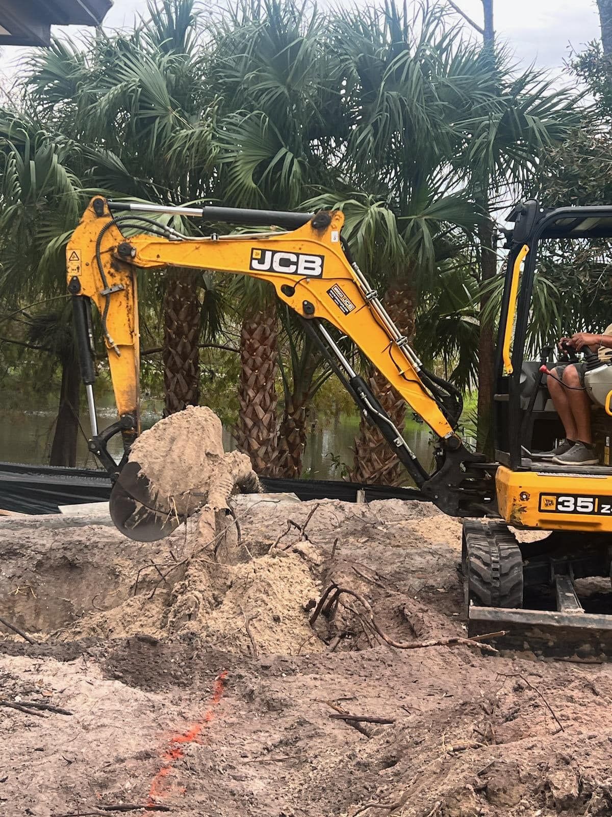A yellow excavator is digging a hole in the ground.