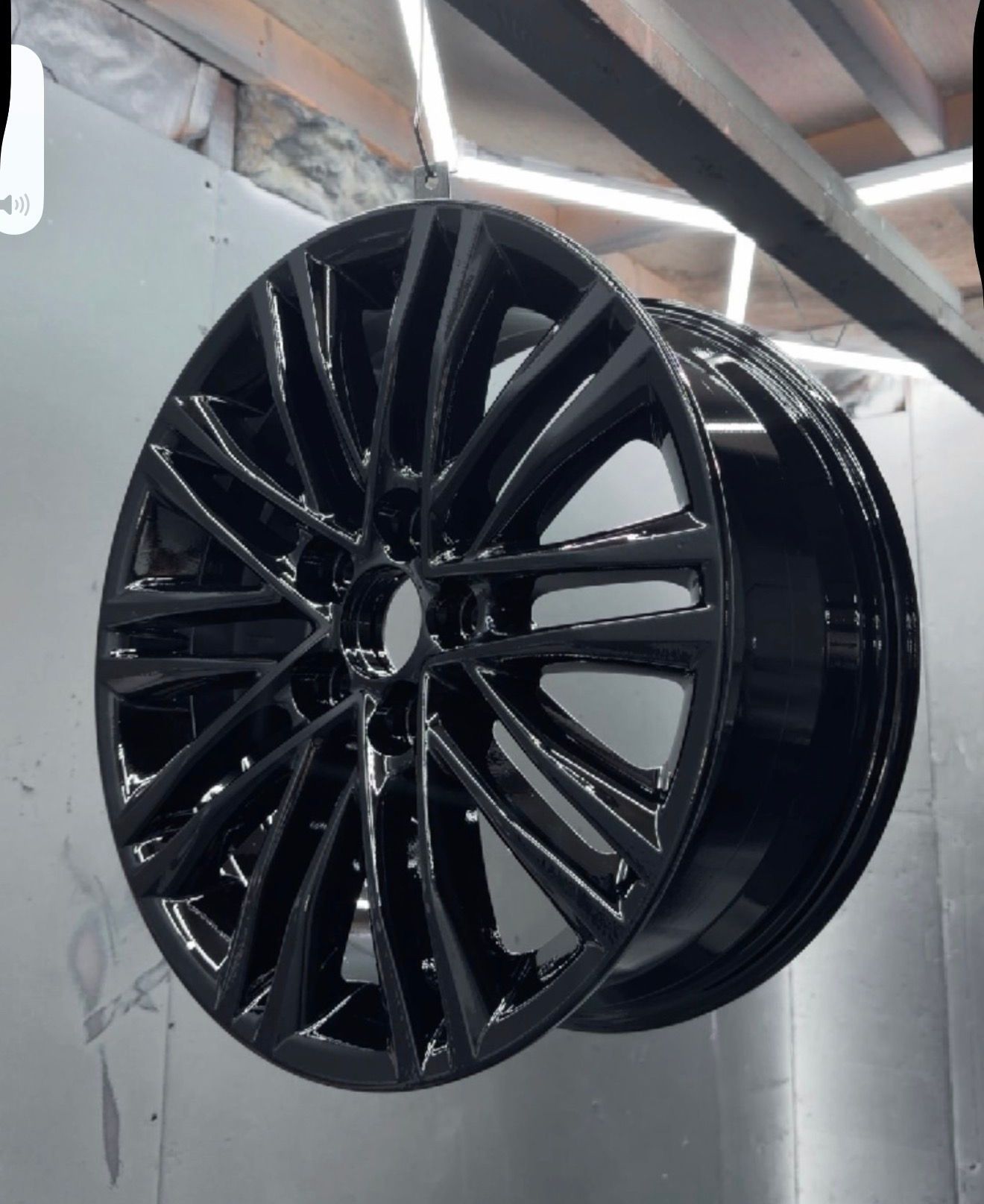 Spray painting a white car wheel rim in a paint booth, with mist from the spray gun.