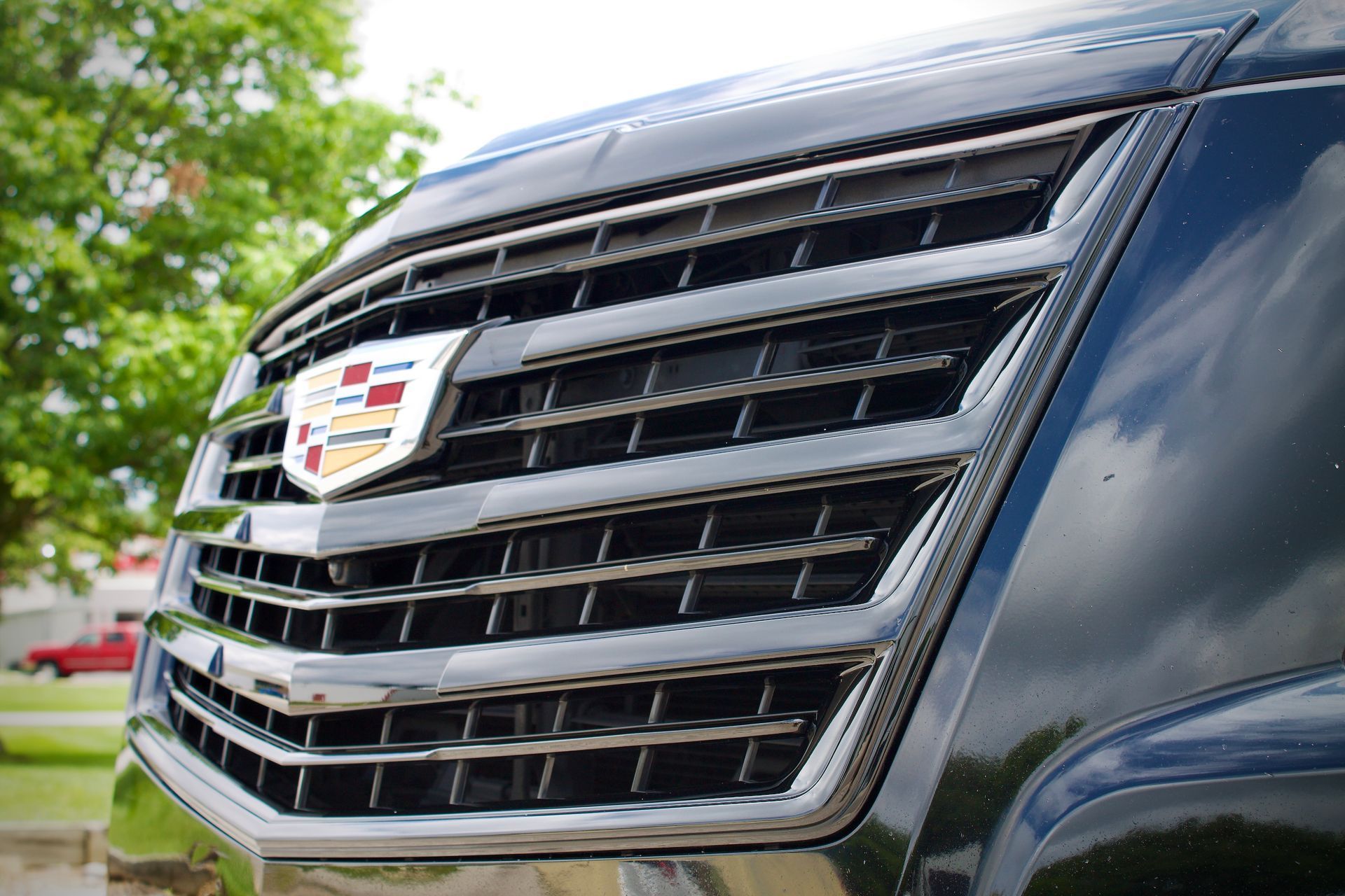 Close-up of a black Cadillac SUV grille with chrome accents and badge outdoors