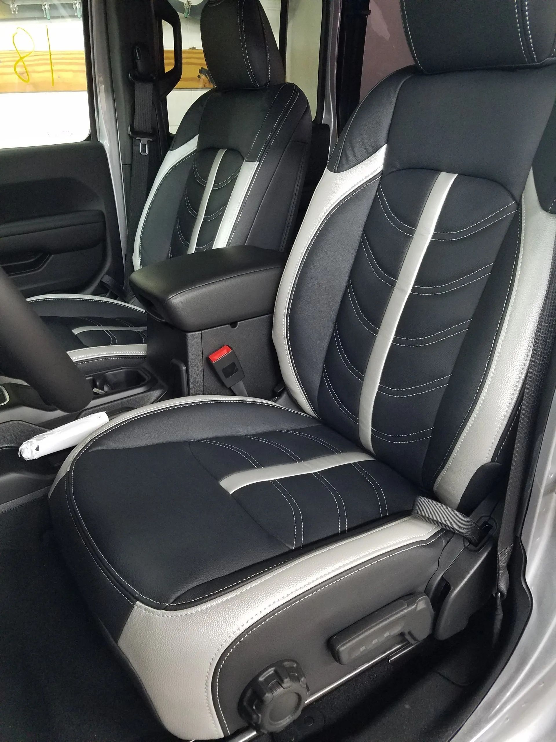 Black and gray car interior with two front seats upholstered in striped fabric and leatherette.