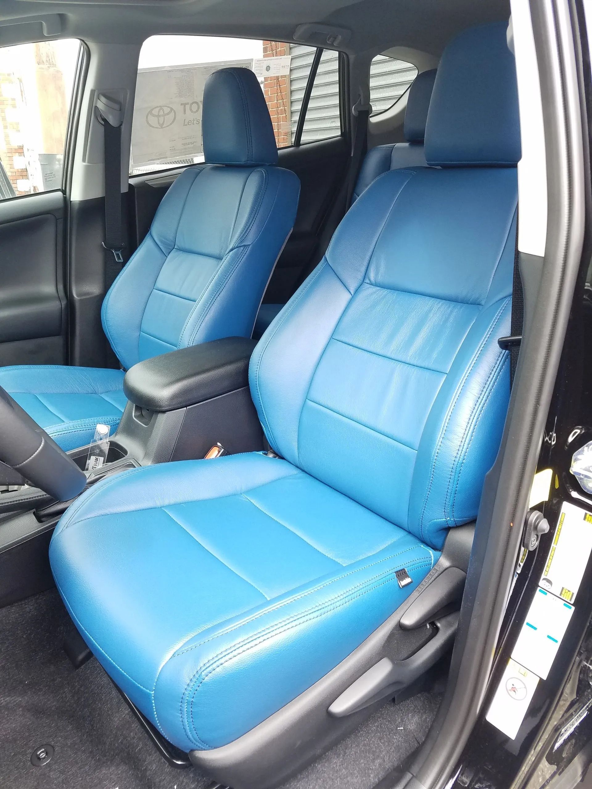 Blue front car seats with a center armrest inside a vehicle