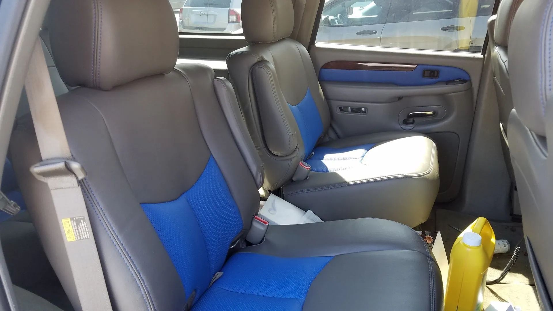 Car interior with blue-and-gray seats and a yellow bottle on the floor.