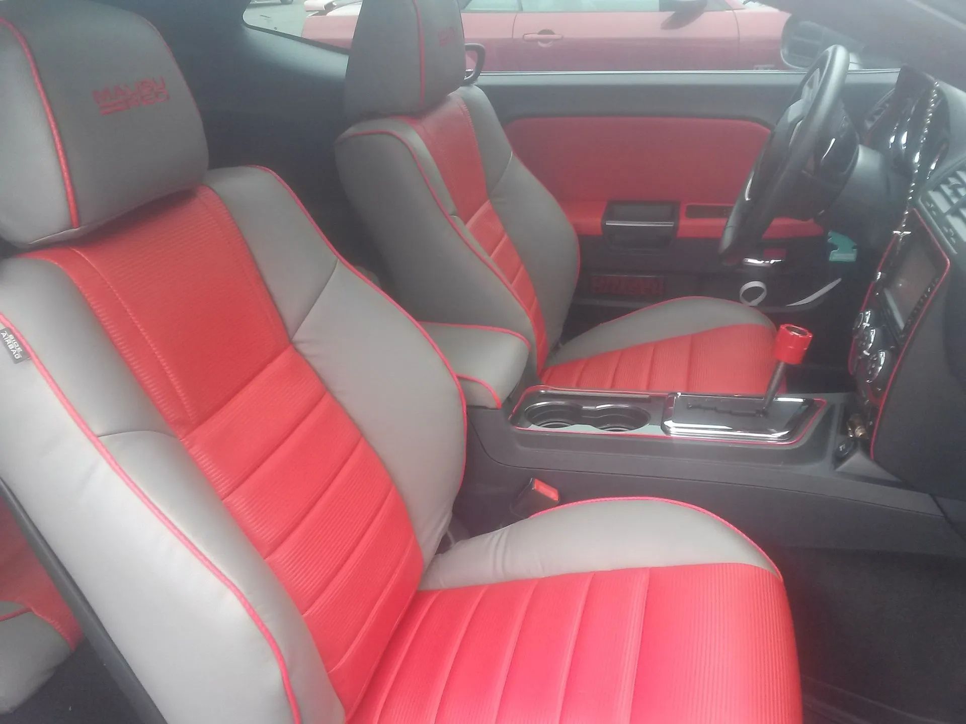 Red and gray car interior with two front bucket seats and center console