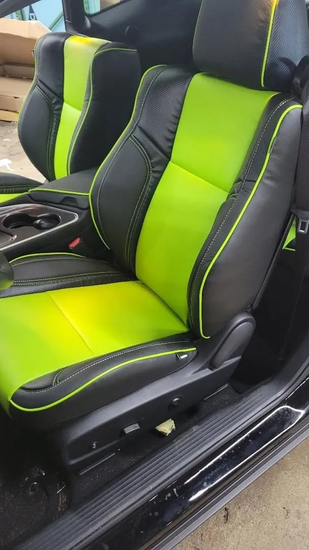 Neon green and black car seat with racing-style bolsters and white stitching in a vehicle interior