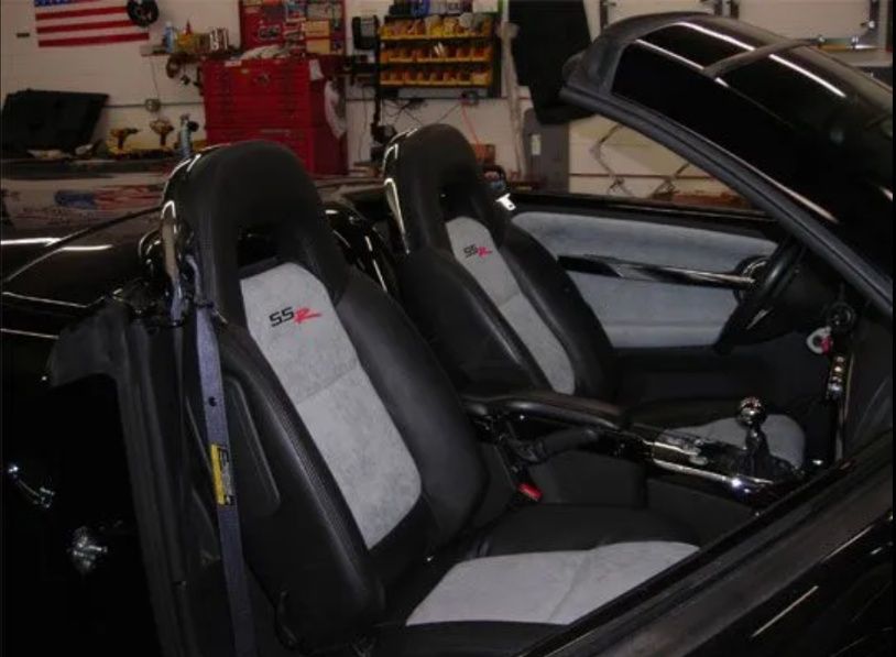 Black convertible interior with gray-and-black racing seats in a garage