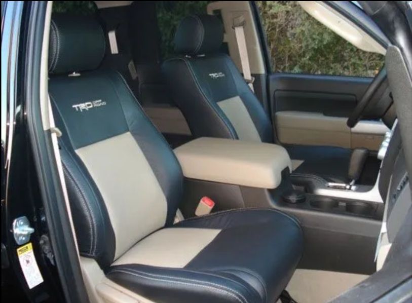 Black-and-gray car interior with two front seats and a beige center armrest