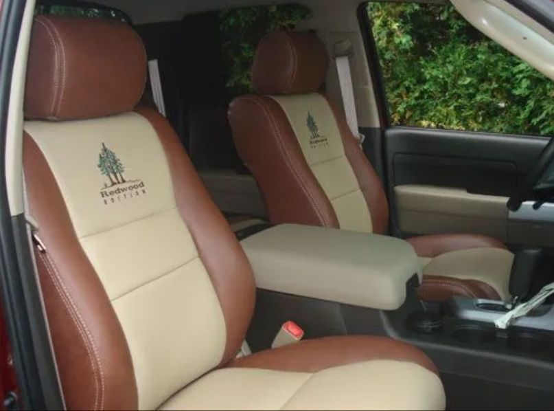 Tan and brown car seats with embroidered logos in a vehicle interior