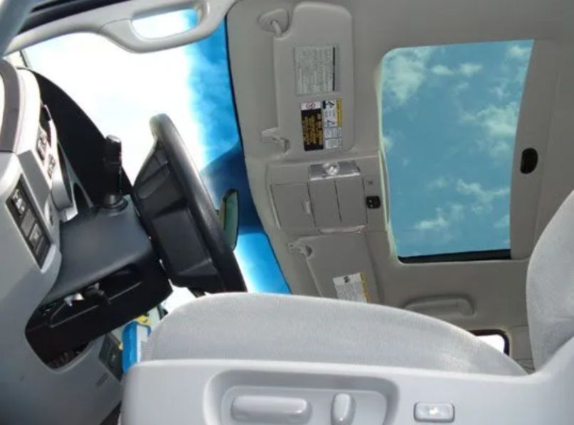 Car interior with sunroof and blue sky visible above the seats