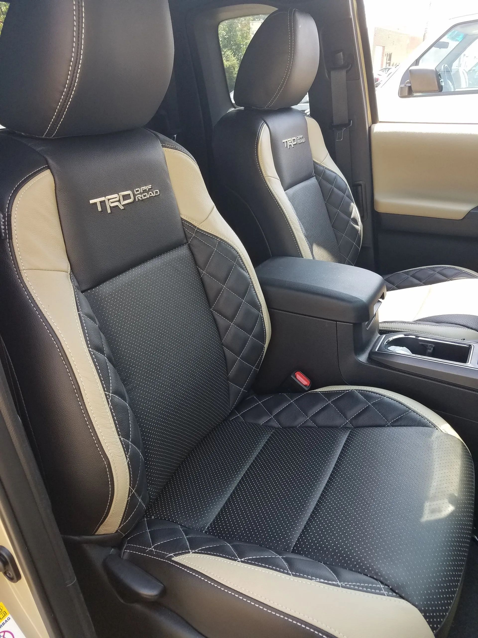 Two black-and-gray front car seats with center console and red seat buckle inside a vehicle